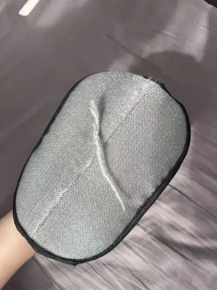 Photo d'avis client : la face tissée grise du gant retient des mèches de poils après un passage sur un textile